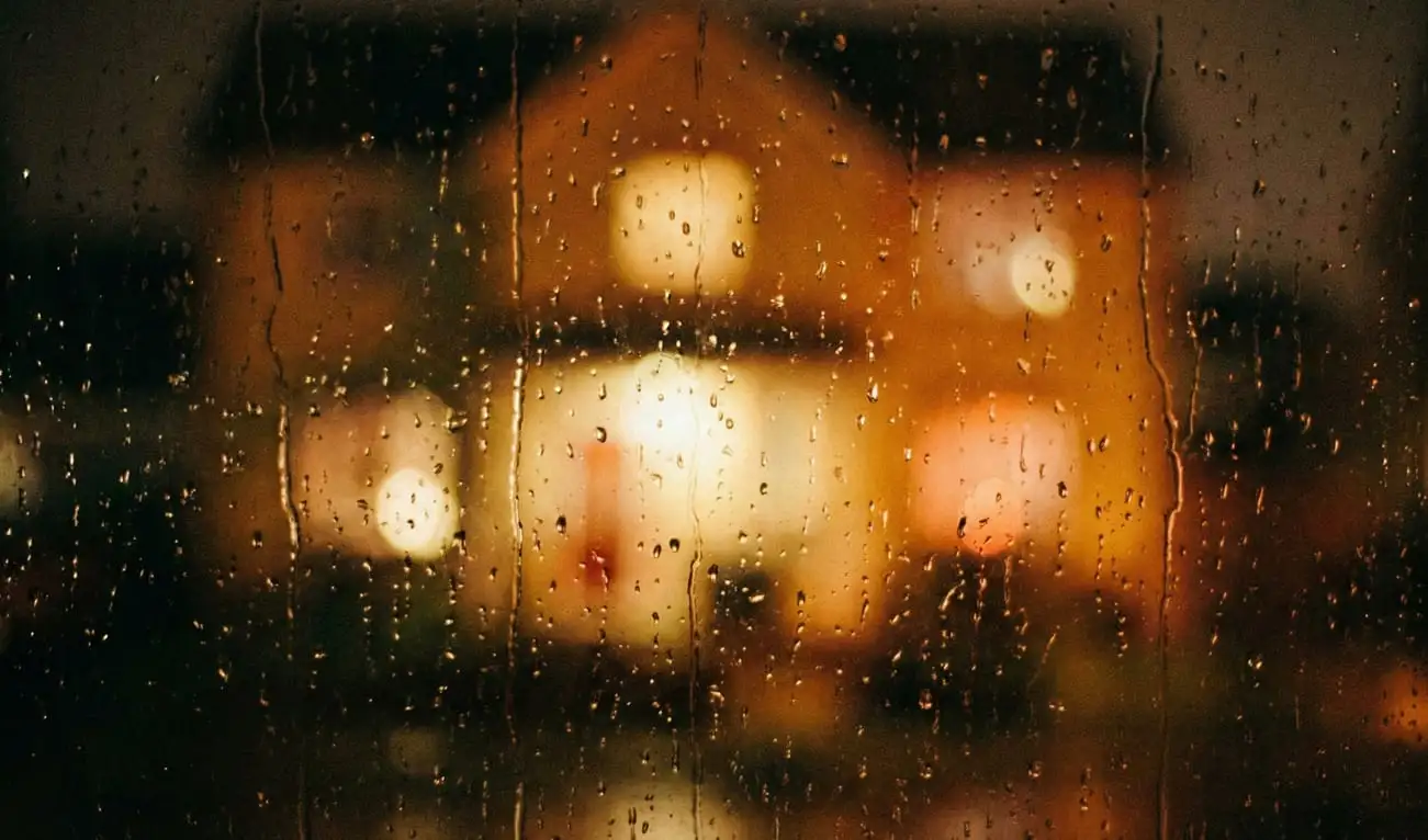 A grainy film photograph taken from inside a dark room, looking out