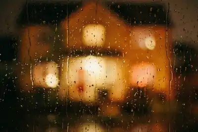 A grainy film photograph taken from inside a dark room, looking out